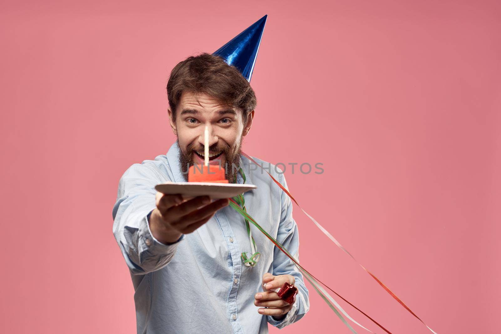 Bearded man with cake tongue on a pink background cropped view and a blue cap on his head by SHOTPRIME