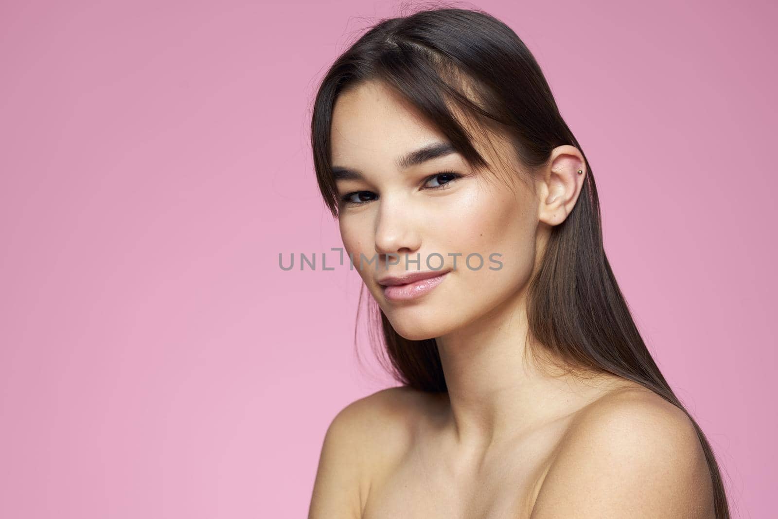 brunette bare shoulders clear skin body care pink background. High quality photo