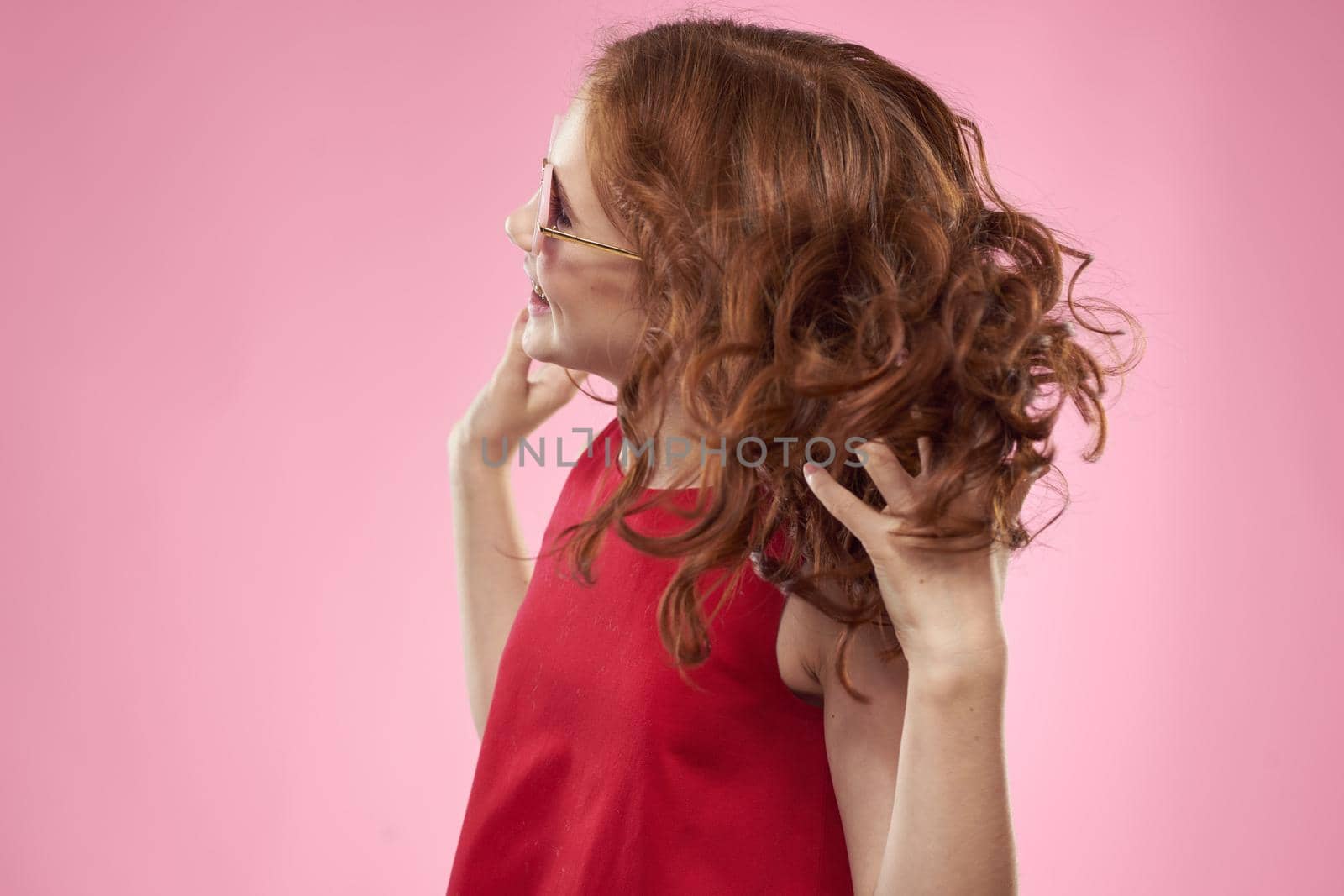 Cheerful little girl childhood dark glasses red dress lifestyle pink background. High quality photo