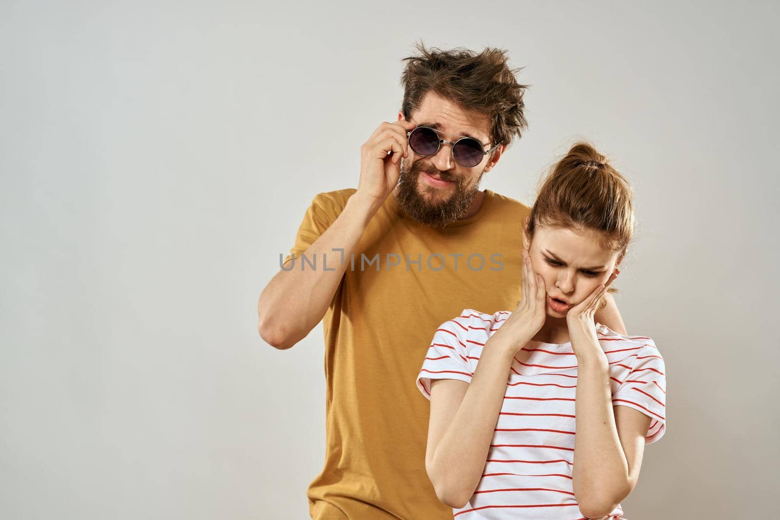 man in sunglasses next to woman in striped t-shirt emotions communication fashion studio fun. High quality photo