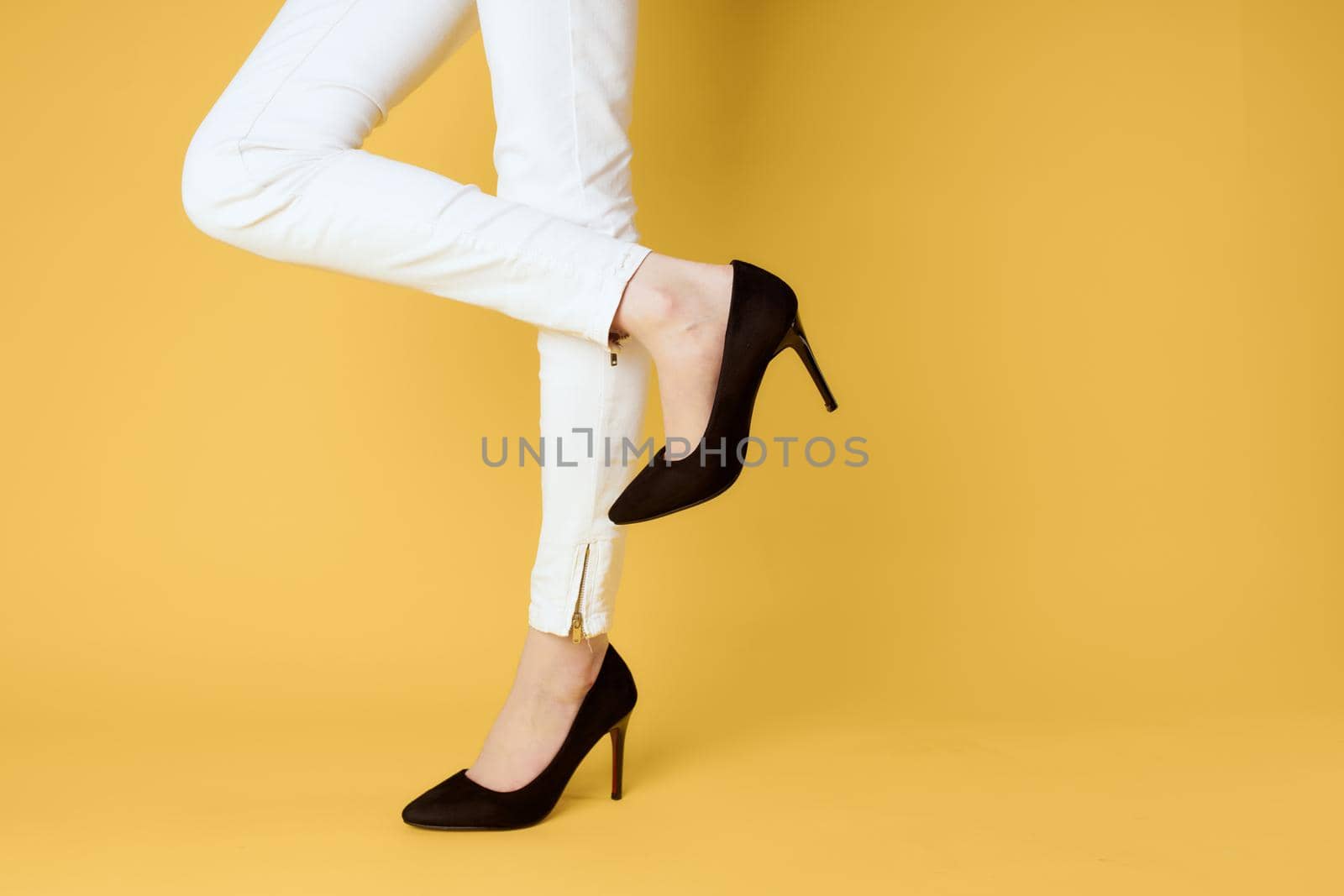 Female feet black shoes fashion clothing studio yellow background. High quality photo
