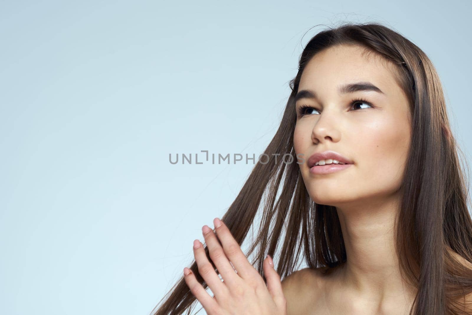 Pretty brunette with bared shoulders long hair body care blue background. High quality photo
