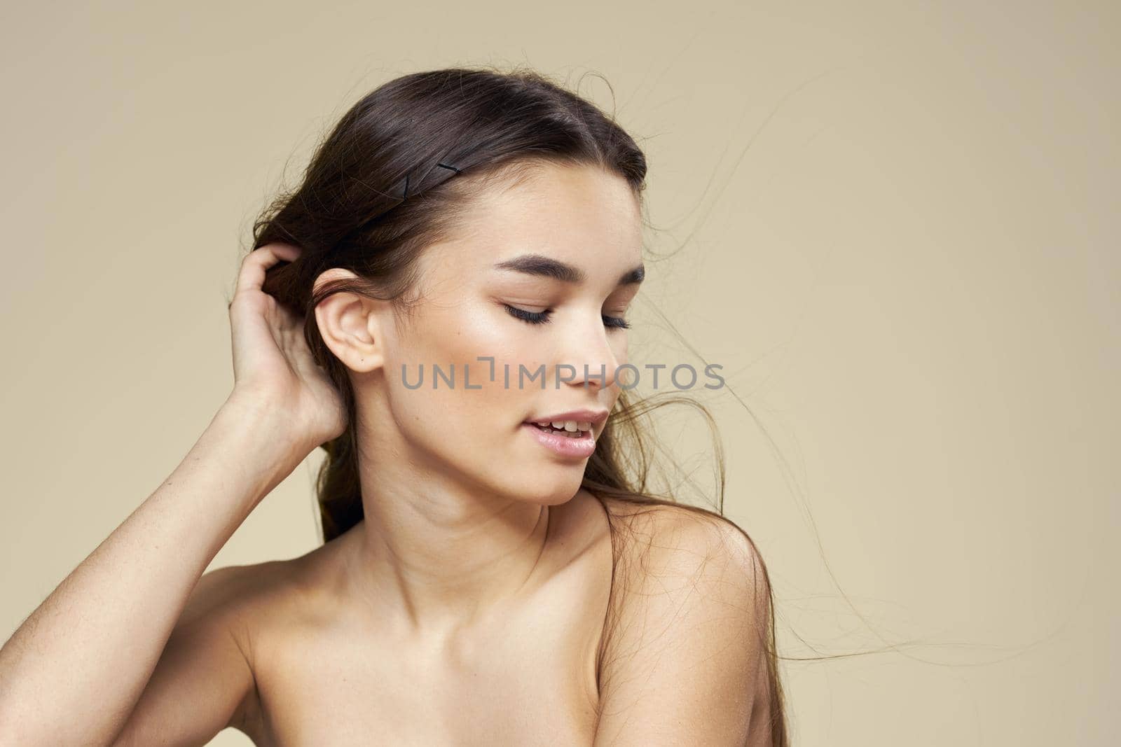 Pretty woman naked shoulders cosmetics clean skin hair care beige background. High quality photo