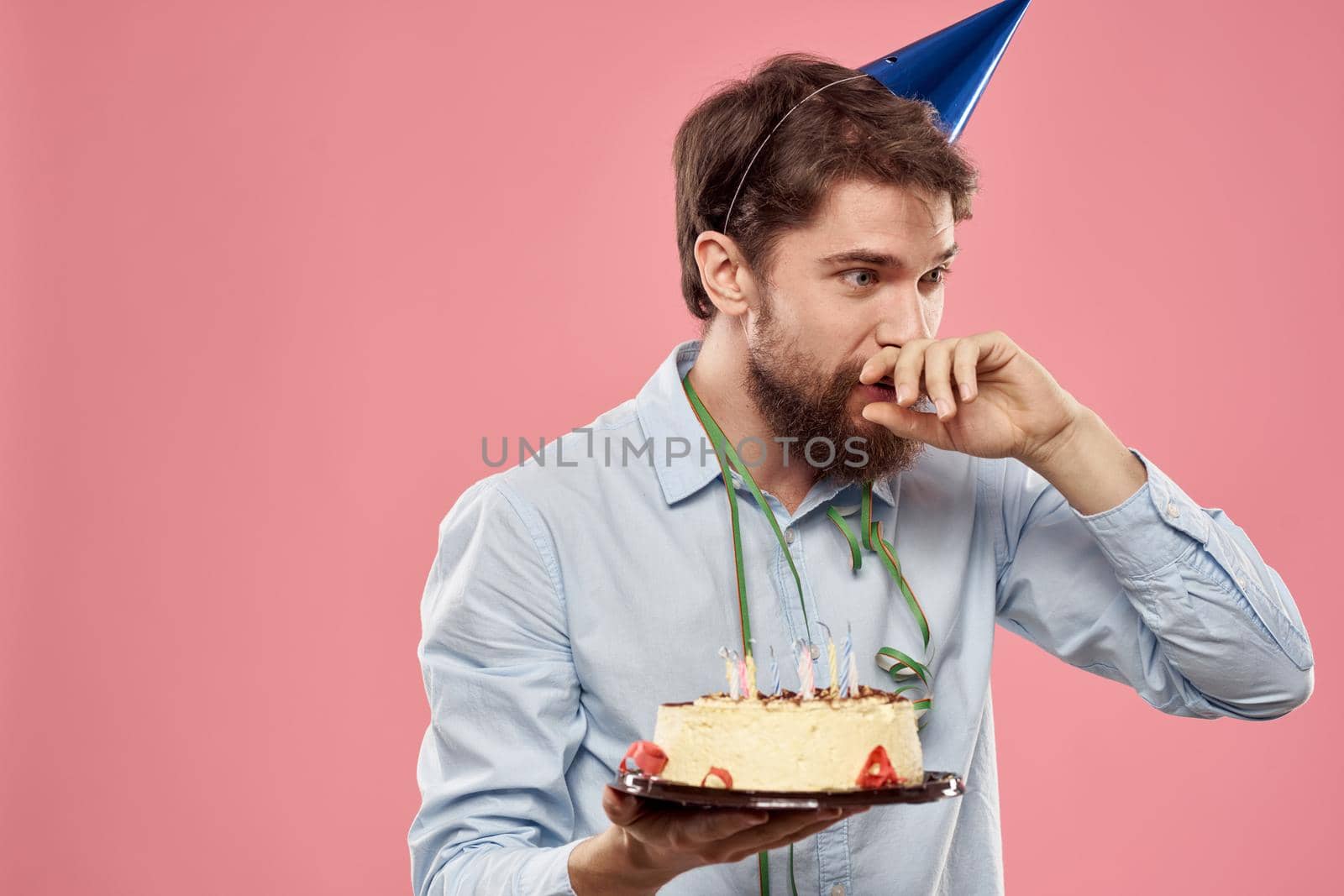 Bearded man with cake on pink background birthday party corporate emotions model loneliness. High quality photo