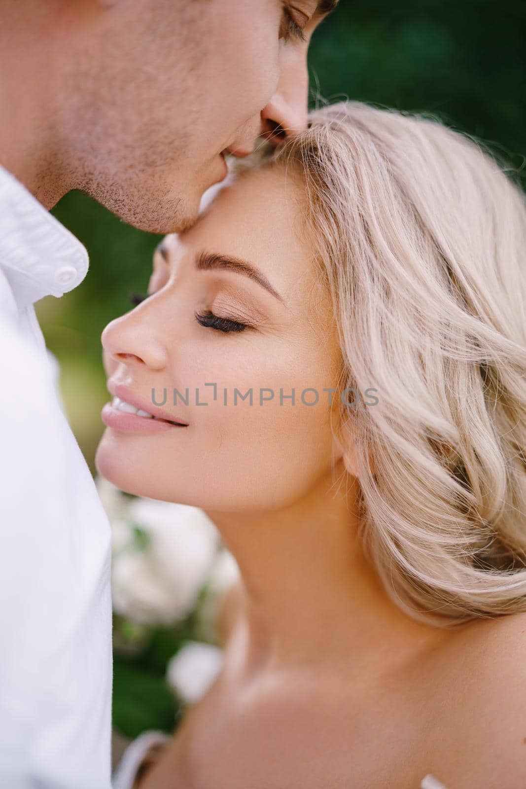 Wedding in Florence, Italy, in an old villa-winery. The groom kisses the bride on the forehead, close-up. by Nadtochiy