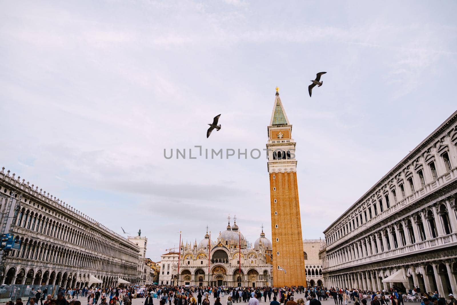 A huge bell tower made of red brick in Piazza San Marco in Venice, Italy. Against background of a cloudy, evening, October sunset sky.