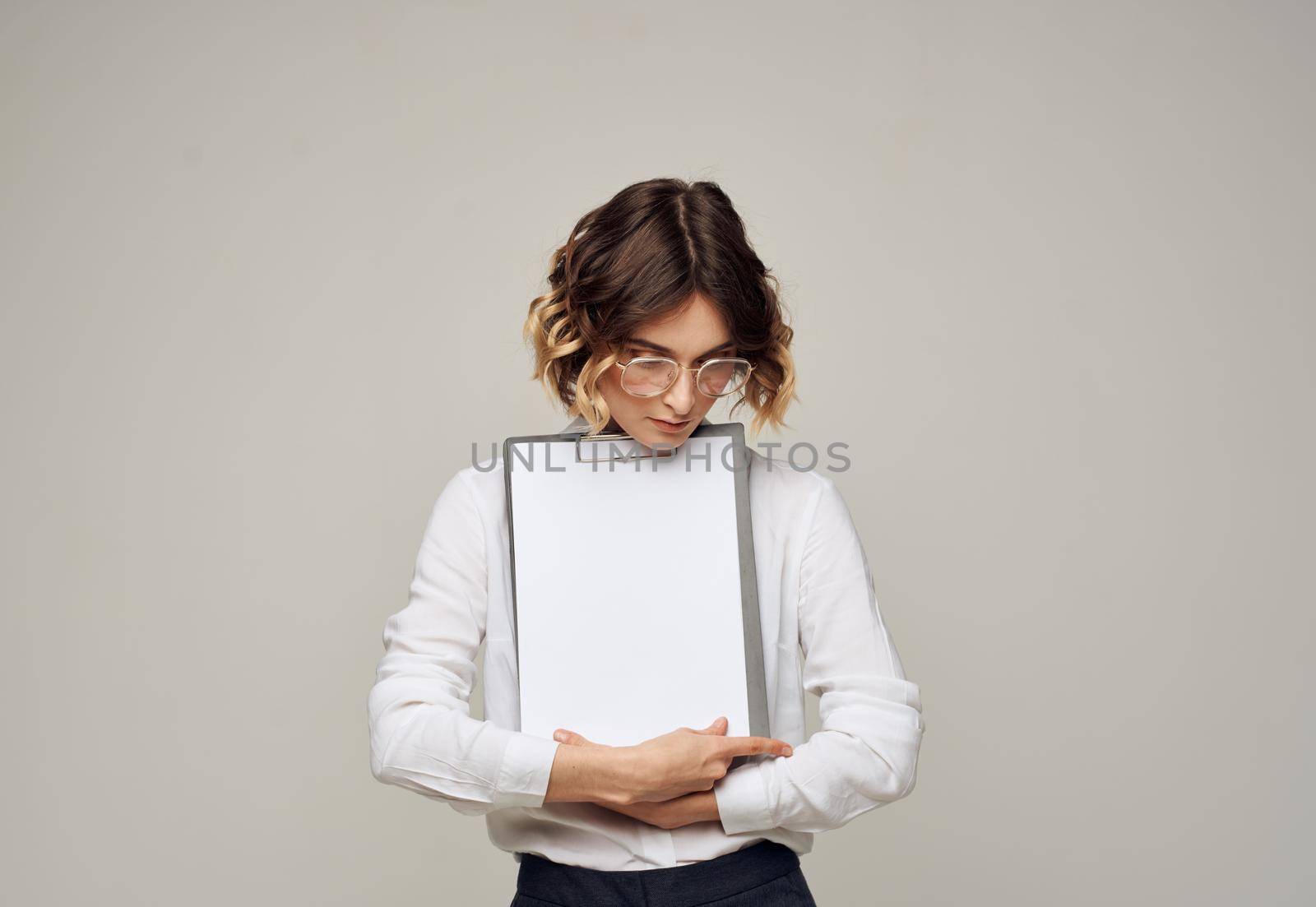Folder with a white sheet of paper on a gray background in the hands of a woman mockup. High quality photo