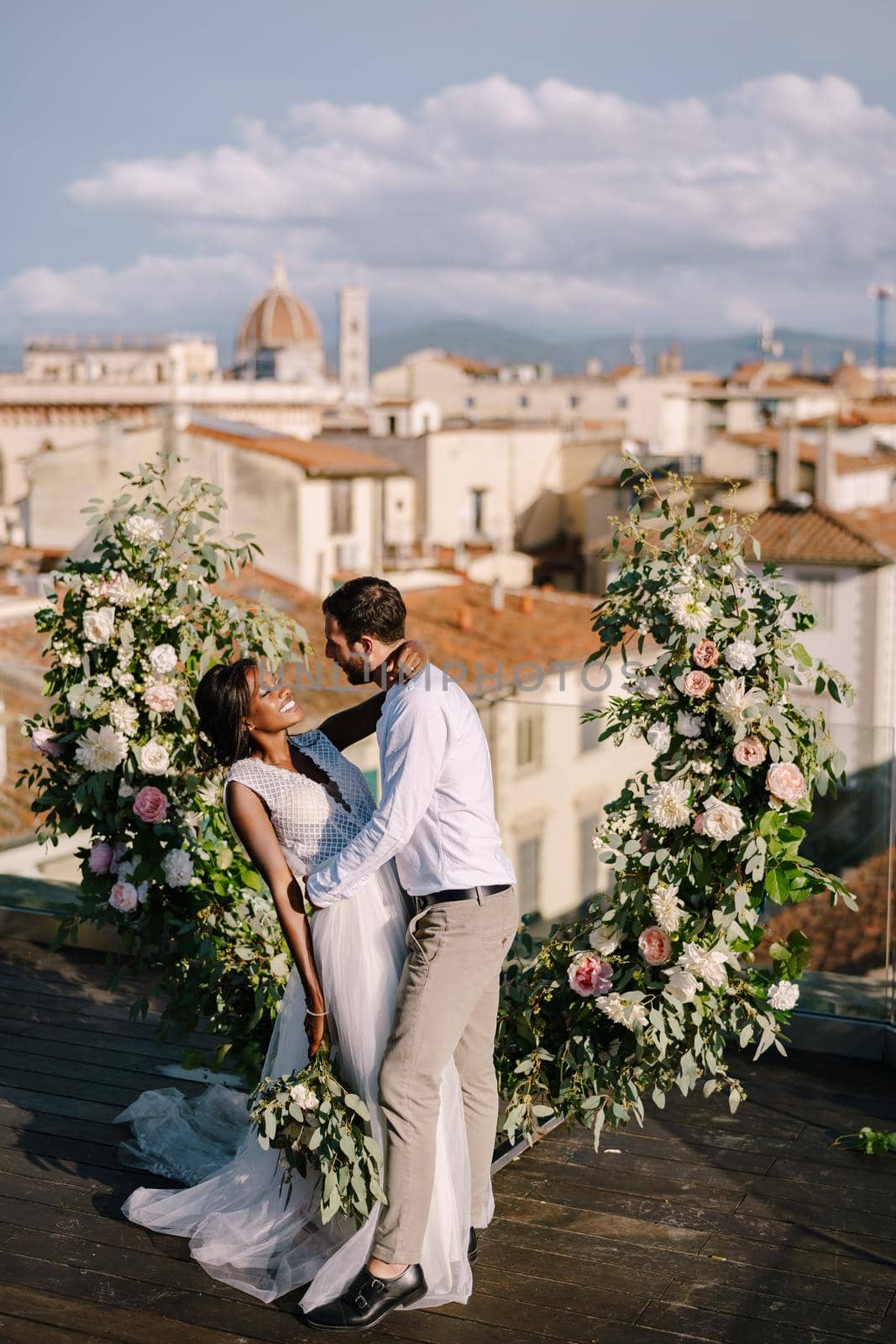 Multiracial wedding couple. Destination fine-art wedding in Florence, Italy. A wedding ceremony on the roof of the building, with cityscape views of the city and the Cathedral of Santa Maria Del Fiore by Nadtochiy