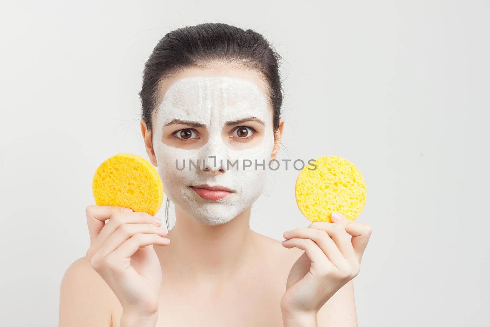 woman with bare shoulders with bum in hands removing mask from face by SHOTPRIME