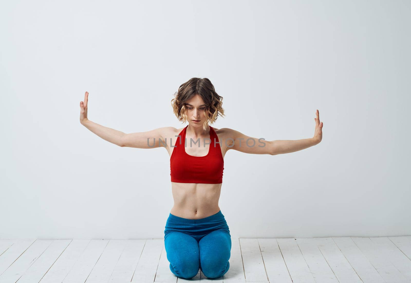 Woman in sportswear on a light background gestures with her hands yoga asana by SHOTPRIME