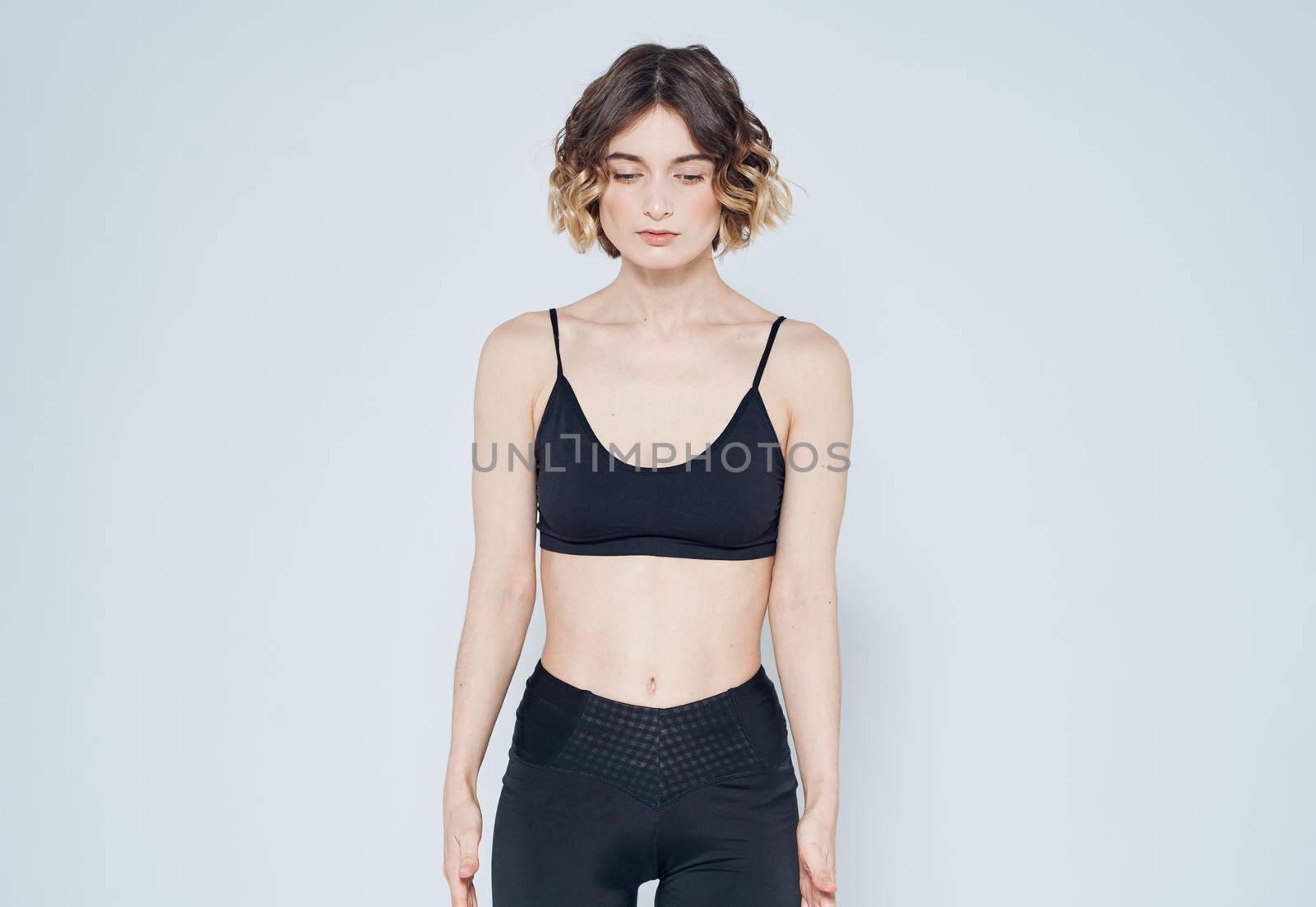 A slender woman with a short haircut goes in for sports on a light background. High quality photo