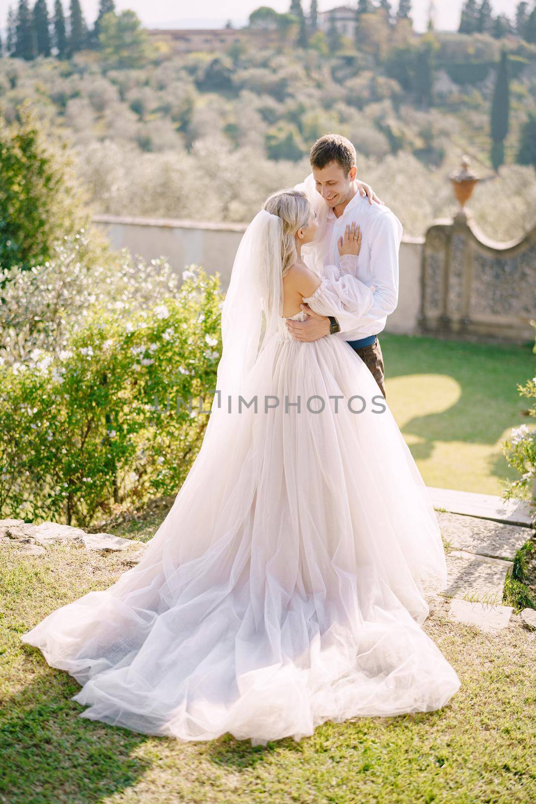 Wedding in Florence, Italy, in an old villa-winery. Wedding couple in the garden at sunset. by Nadtochiy