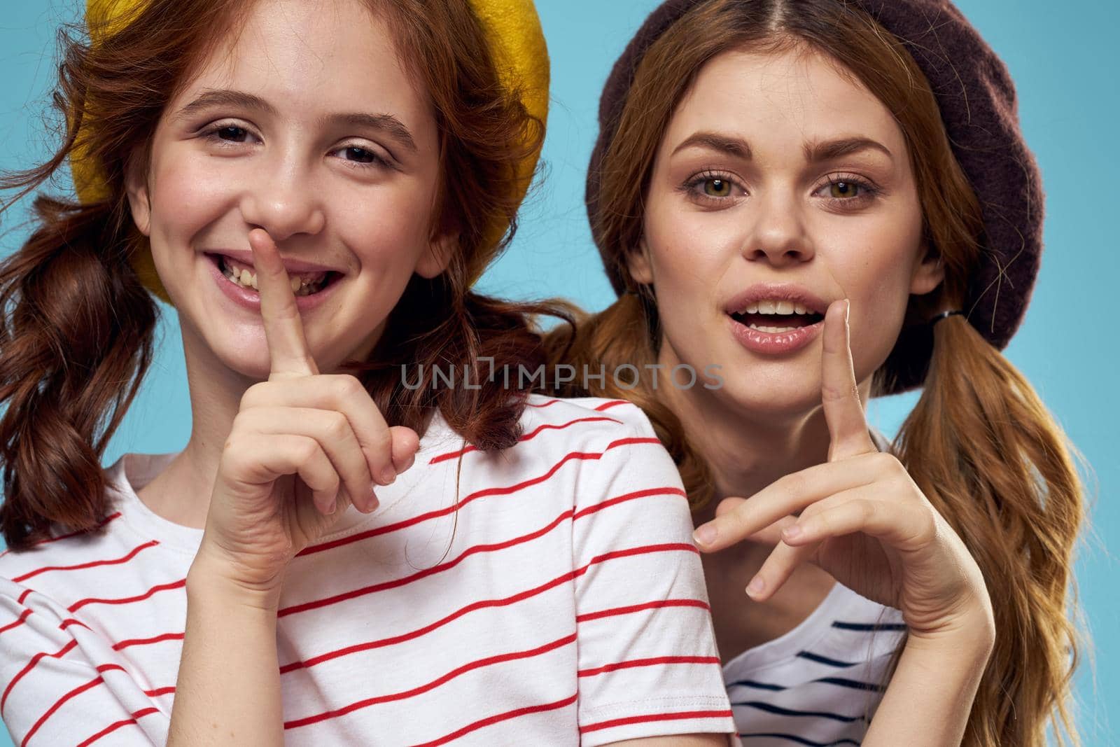 Cheerful girl and woman on a blue background sisters family emotions. High quality photo