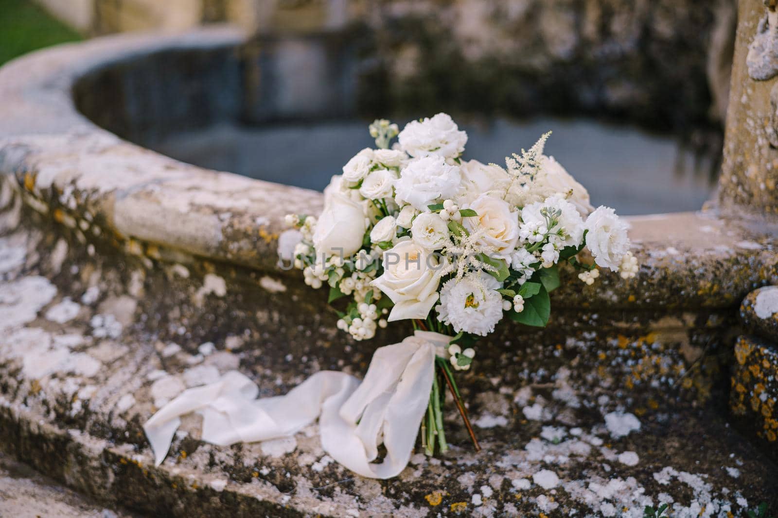 White bride bouquet on an old fountain.