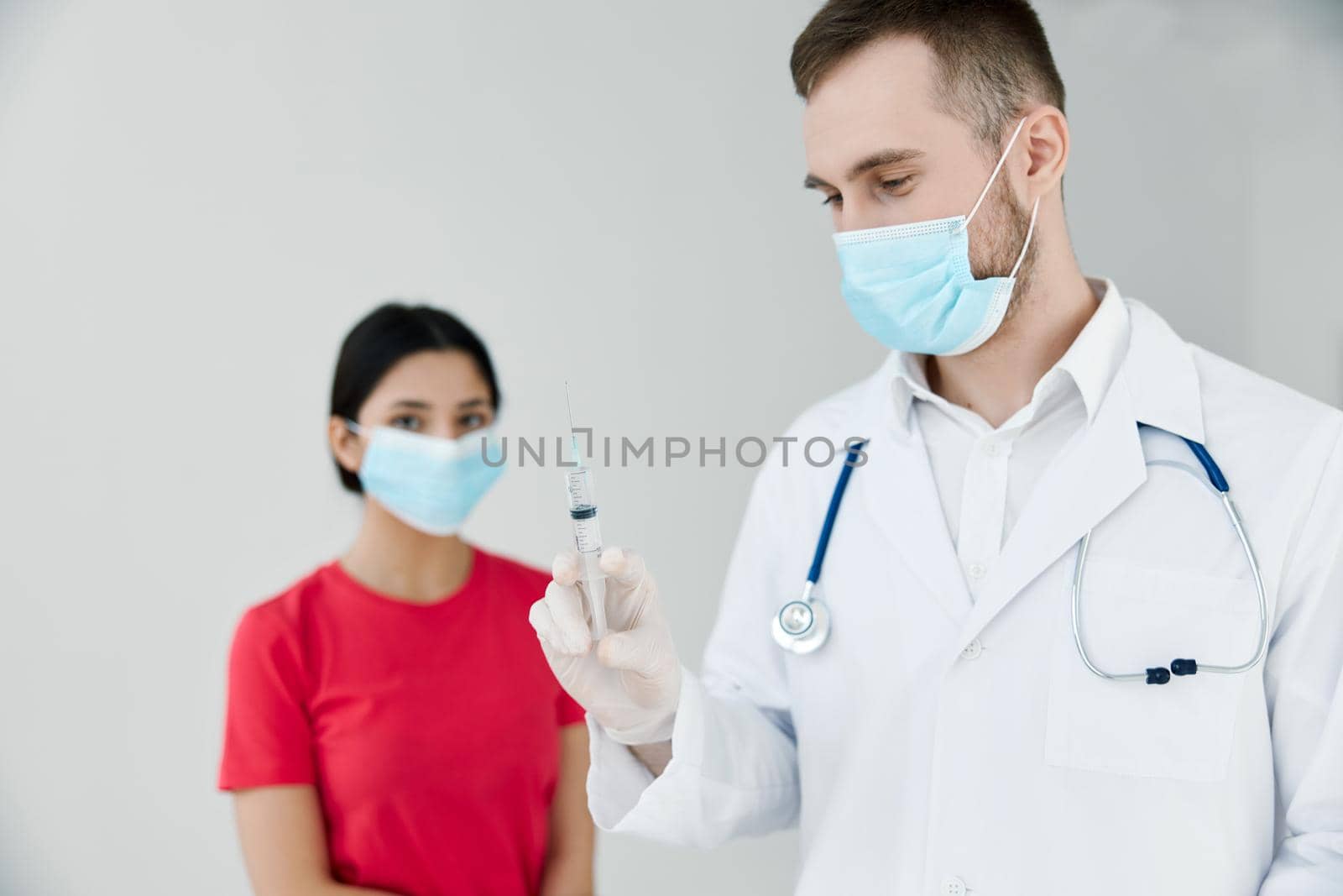 male doctor holding an injection next to a female patient. High quality photo