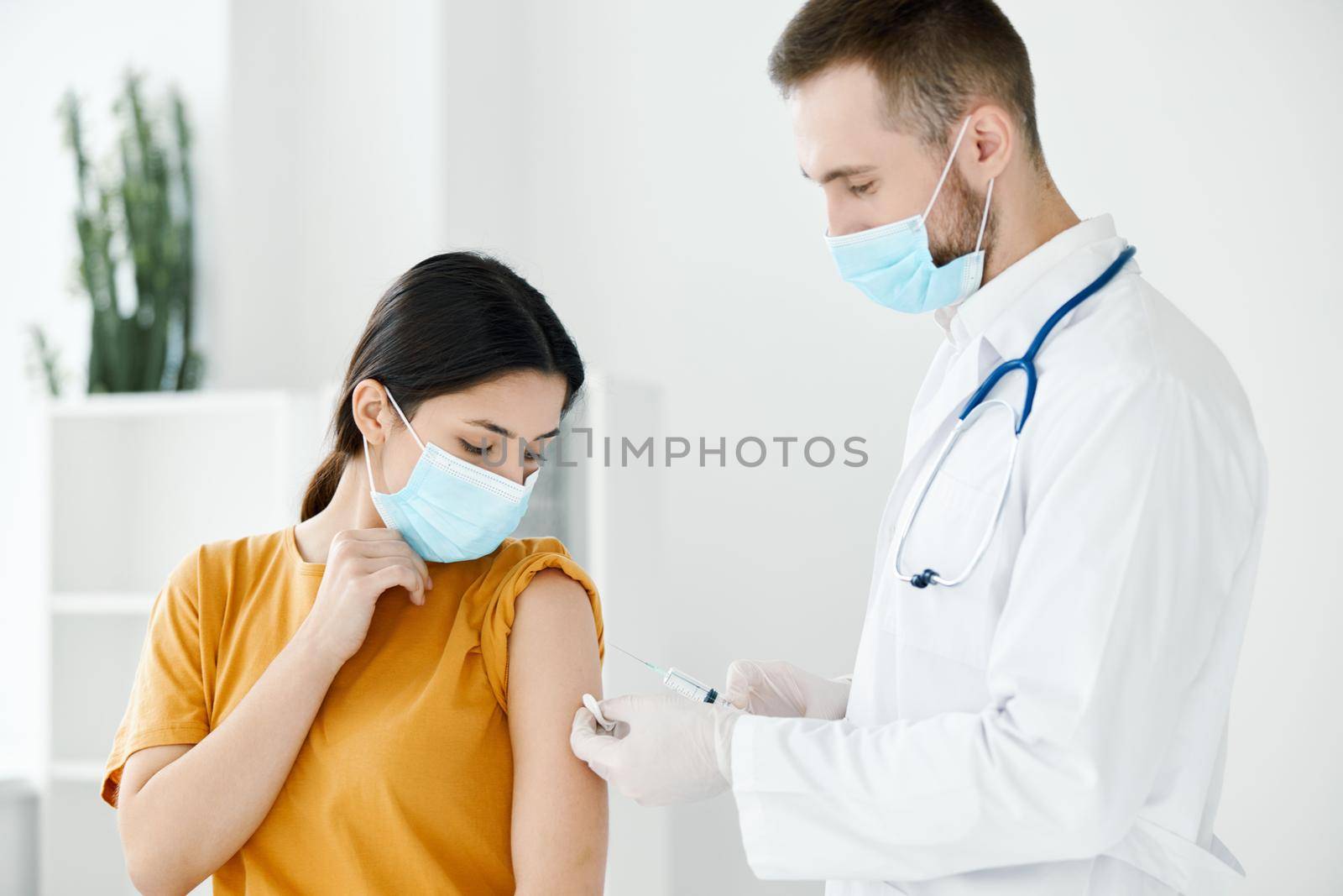 doctor giving a shot to the woman's shoulder medical mask covid-19 vaccine. High quality photo