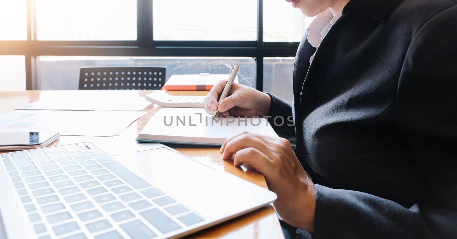 A woman hand holding a pen note some data on notepad for financial calculating.