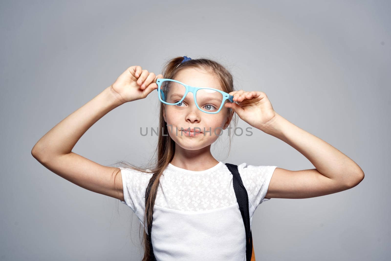 Cute little girl backpack training school studio gray background. High quality photo
