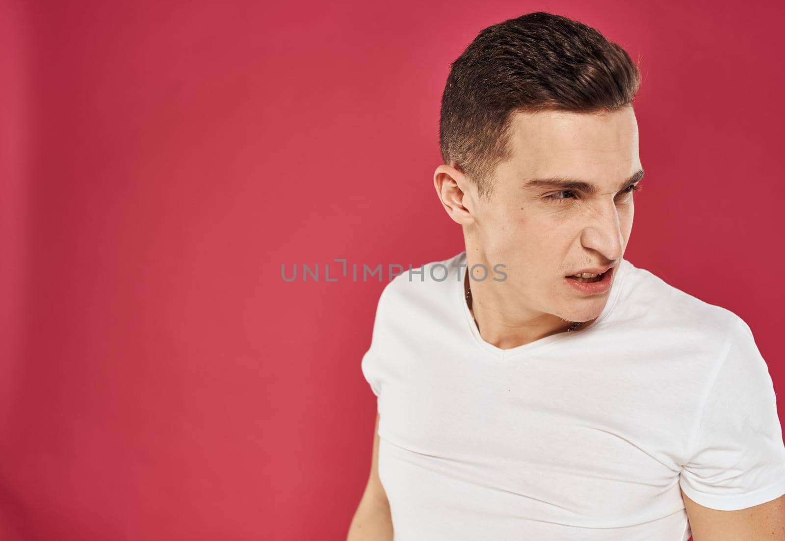 emotional man in white t-shirt studio dissatisfaction red background by SHOTPRIME