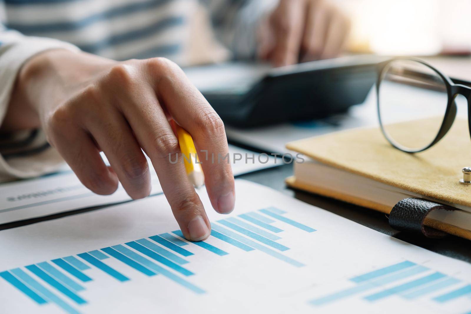 Business woman working in finance and accounting Analyze financial budget with calculator in the office.