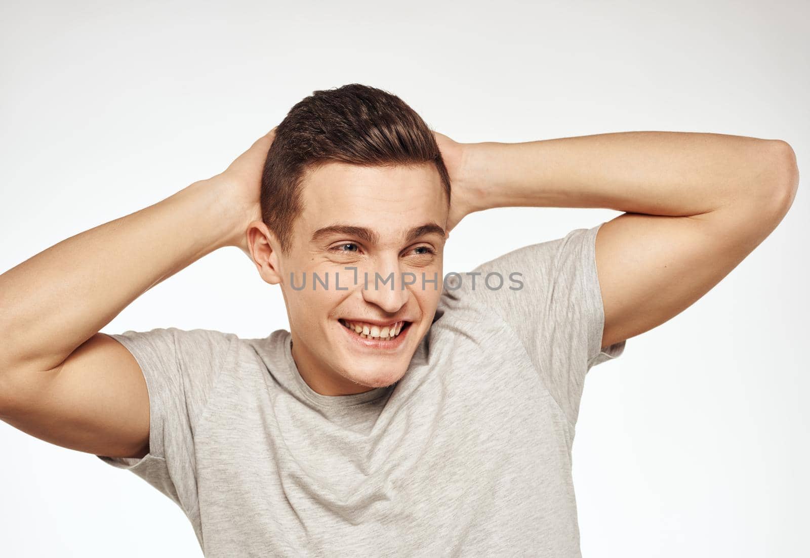 Cheerful man gesturing with his hands on a gray Studio T-shirt. High quality photo