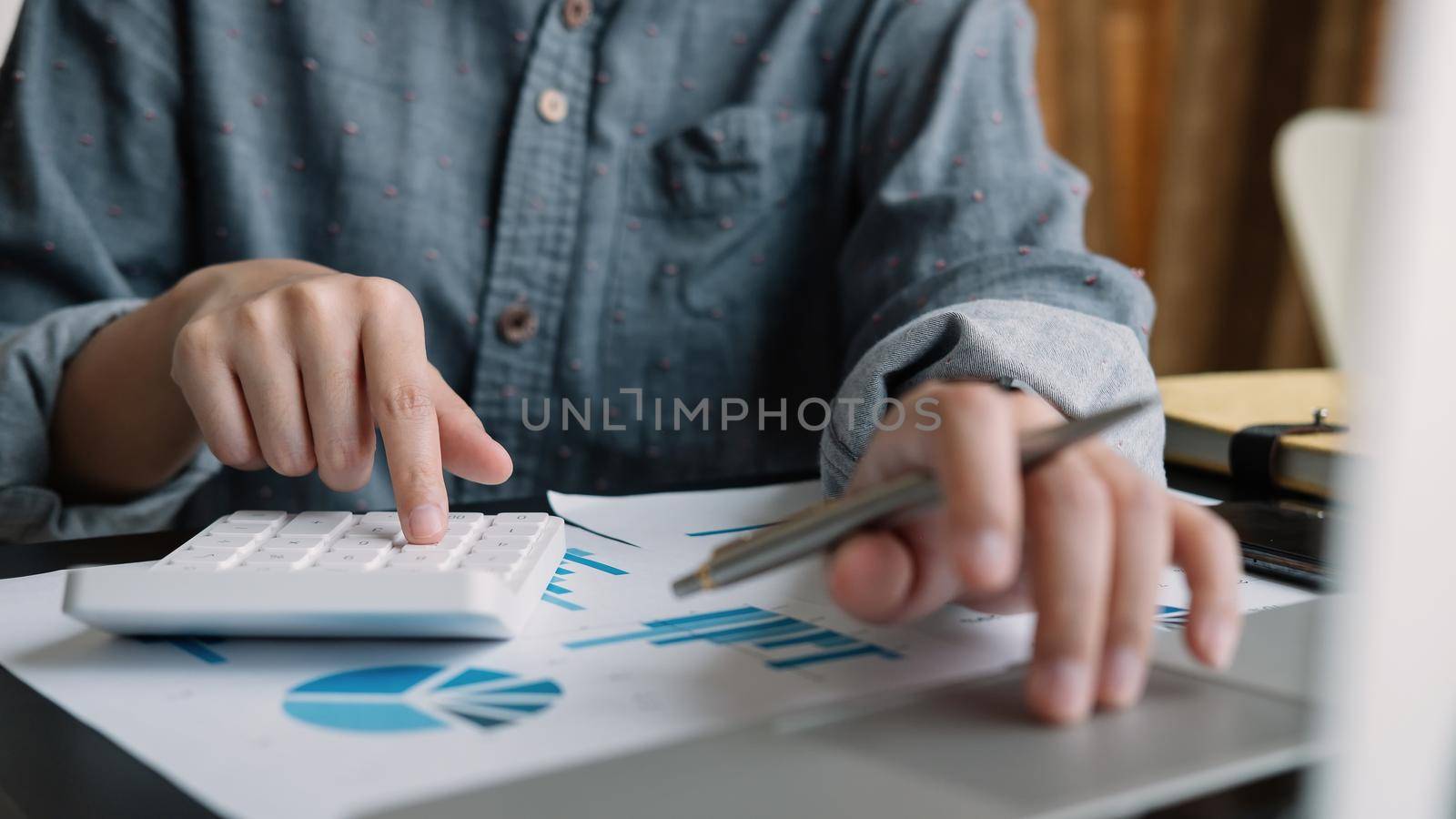 Business woman or accountant working on calculator and laptop computer with financial document, graph diagram and calculator on office table, work from home concept