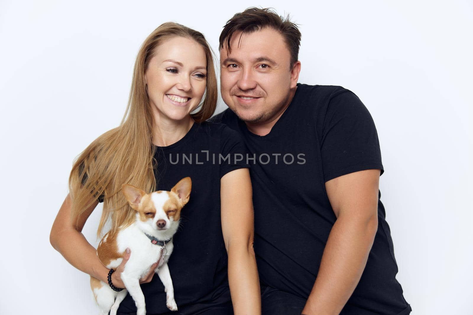 cheerful married couple in black T-shirts hugs a purebred small dog. High quality photo