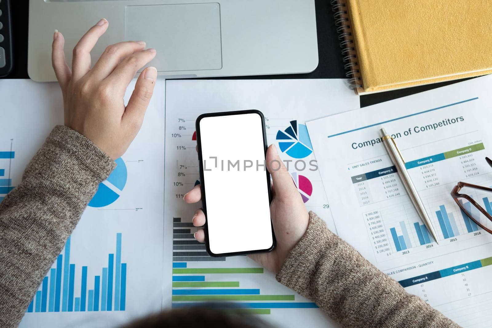 Top view of business woman using smartphone with blank white screen and laptop computer for accounting and financial, work at home