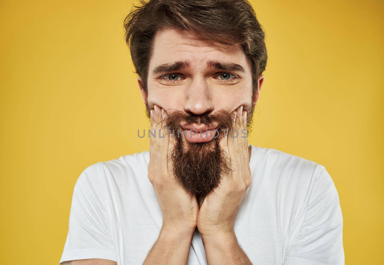 Frightened sad man touching face with hands on yellow background cropped view by SHOTPRIME