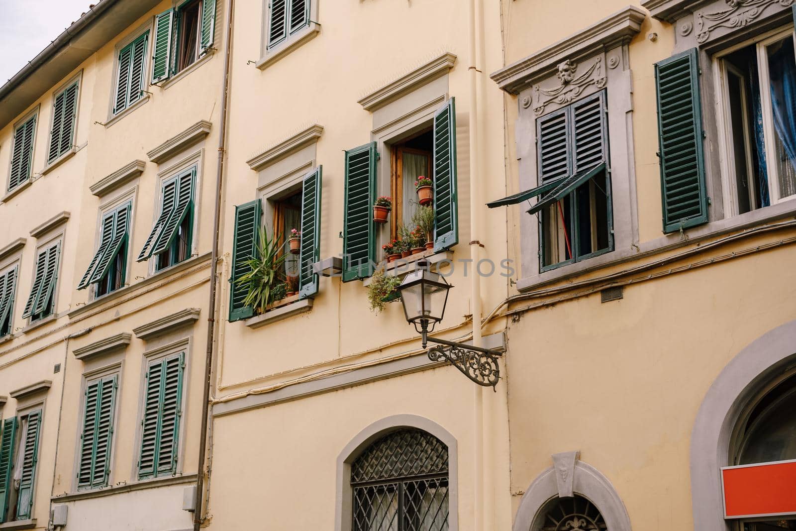 Facade of a residential building in Florence, Italy, with green wooden shutters.