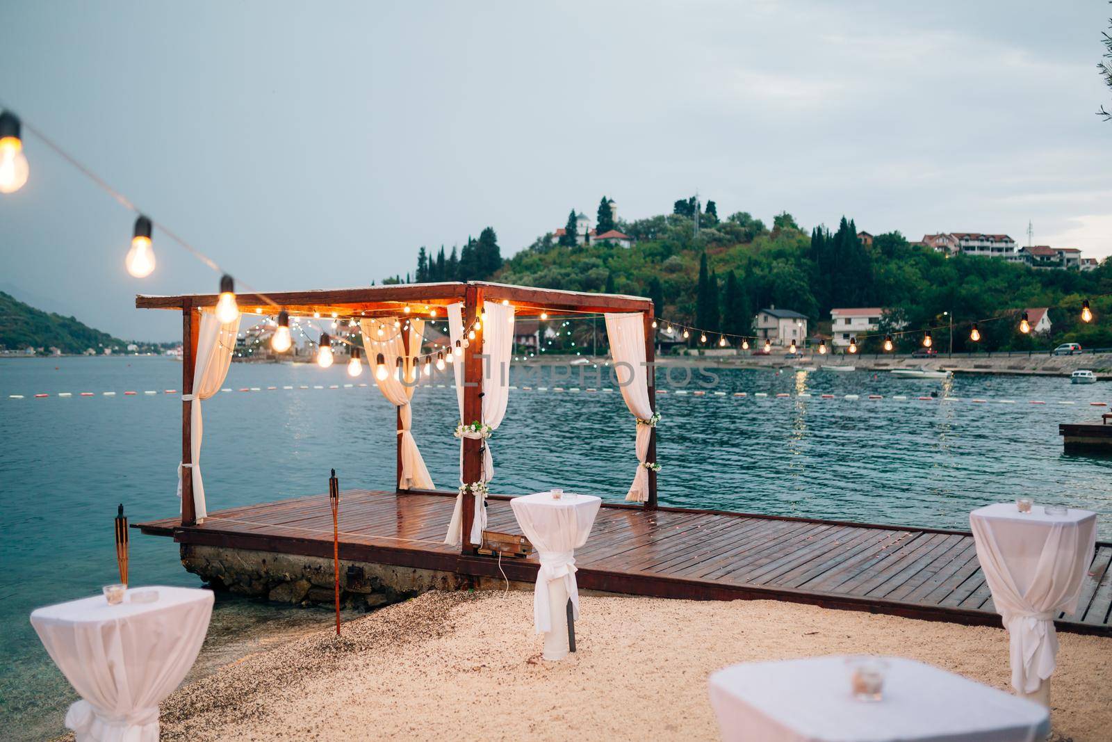 Wedding party on the beach near the gazebo decorated with garlands