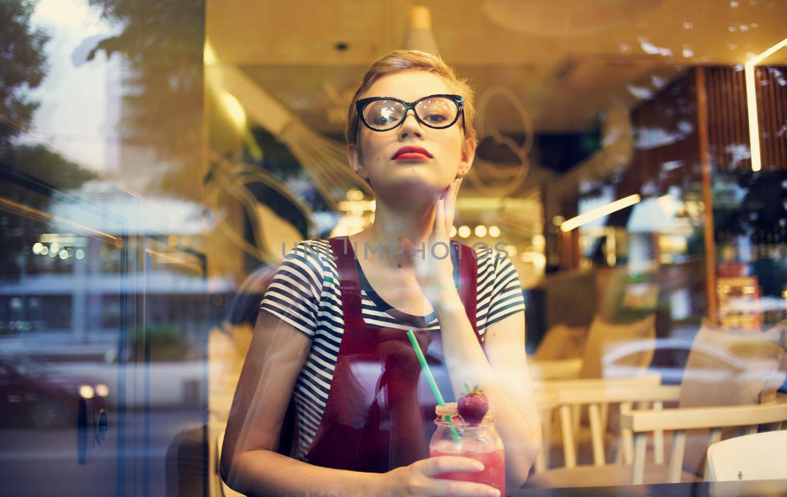 fashionable woman in red sundress resting in a cafe with a drink in her hand. High quality photo