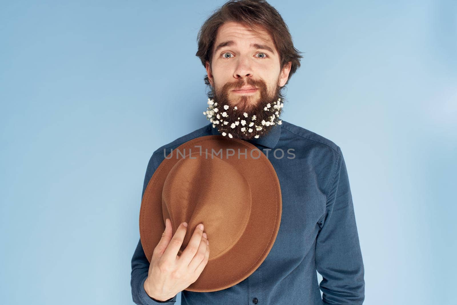 man in shirt flowers in beard hat emotions elegant style blue background. High quality photo
