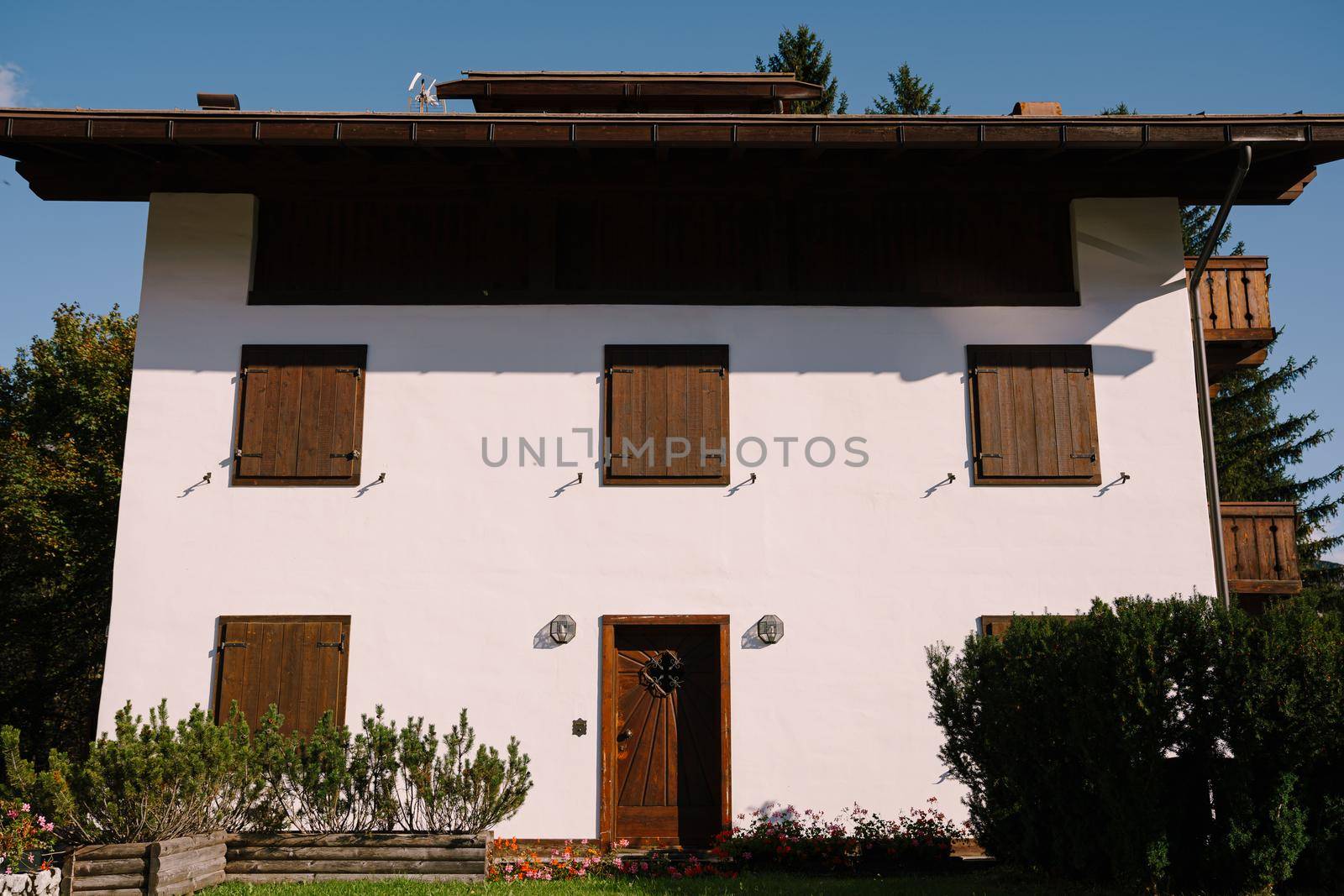 White whitewashed house, with wooden elements in northern Italy, in the Dolomites area, in a winter ski resort, in the city of Cortina Ampezzo.