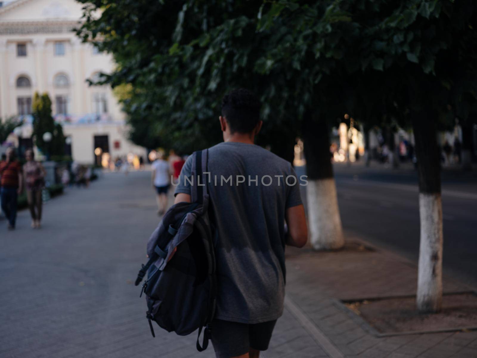 A man walks down the street in nature near buildings in the city by SHOTPRIME