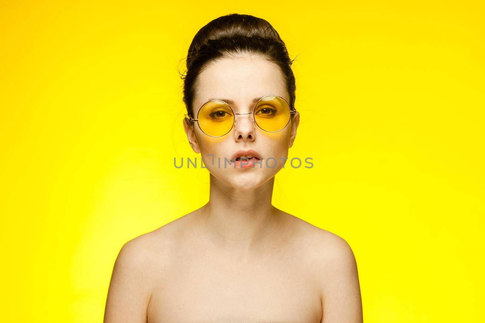 woman naked shoulders surprised look yellow glasses isolated background. High quality photo