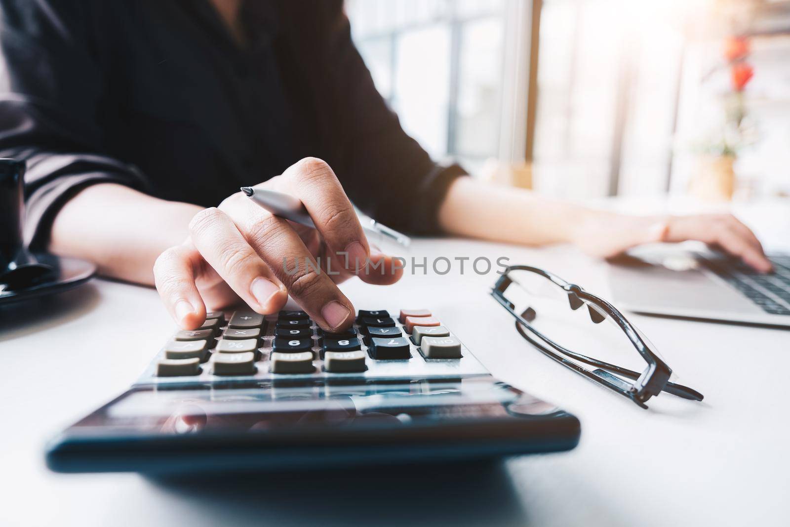 Close up Business woman using calculator and laptop for do math finance on wooden desk in office and business working background, tax, accounting, statistics and analytic research concept by nateemee