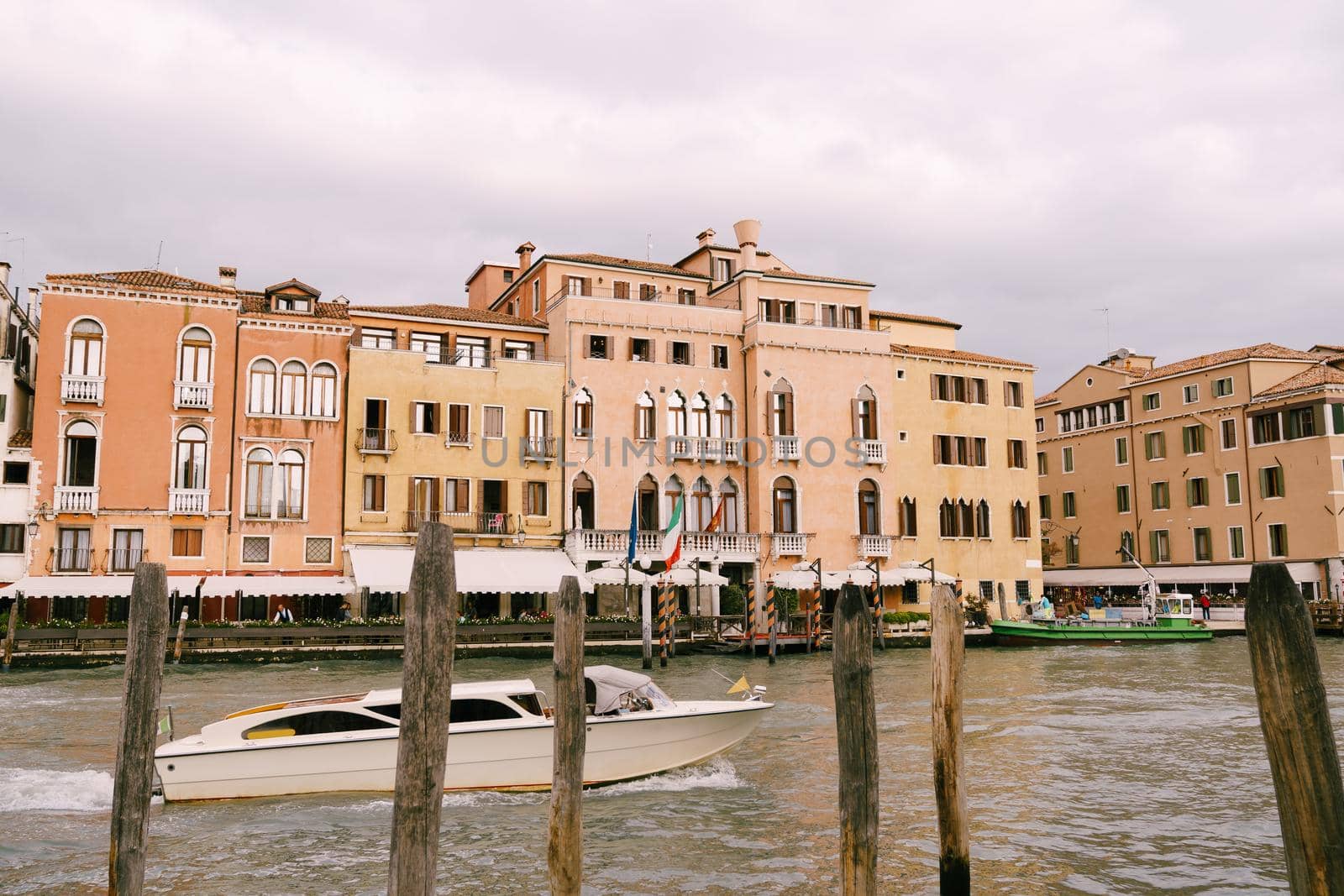 Tourists on the waterfront in Venice, against the background of the ancient facades of buildings standing in water. Water sightseeing in Venice, Italy.