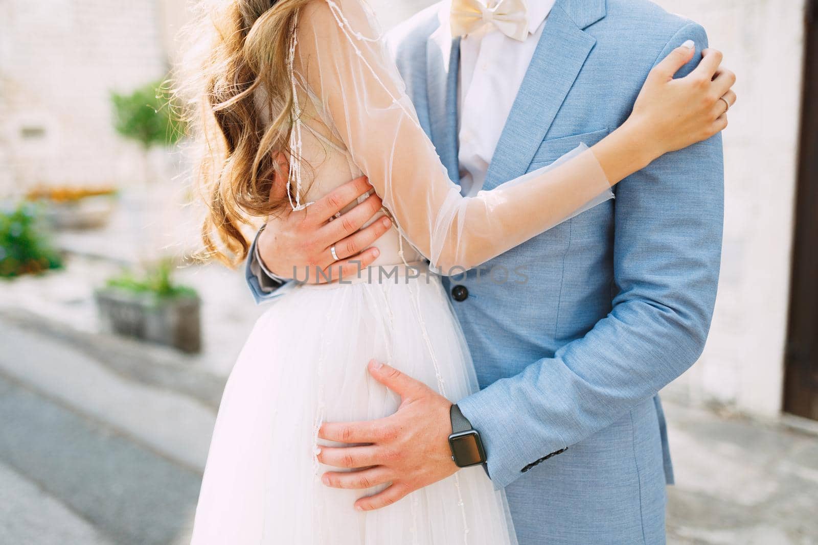 The bride and groom are tenderly embracing on the street of the old town of Perast, close-up by Nadtochiy