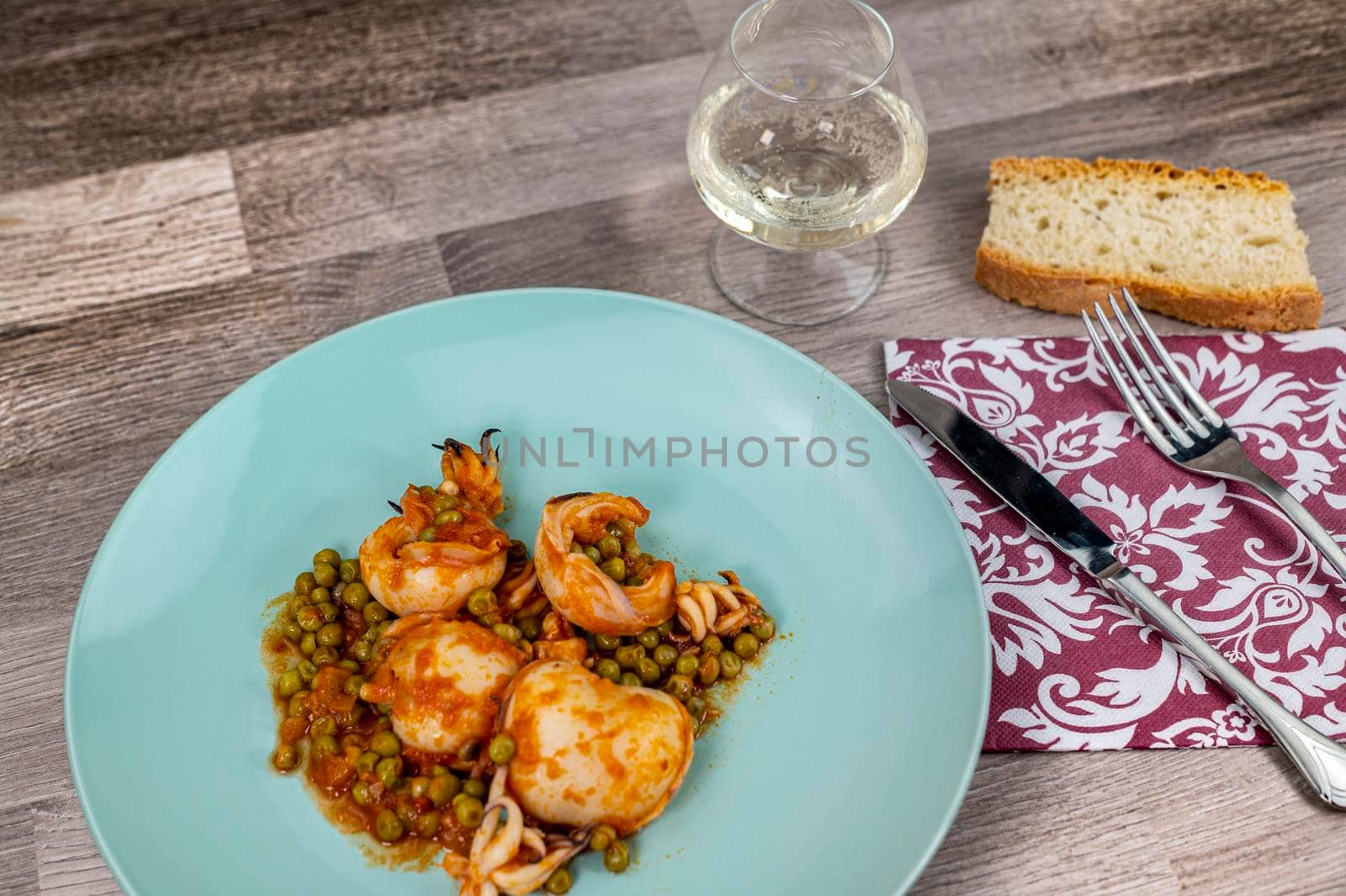 flat composition cuttlefish and peas with glass of wine cutlery and bread