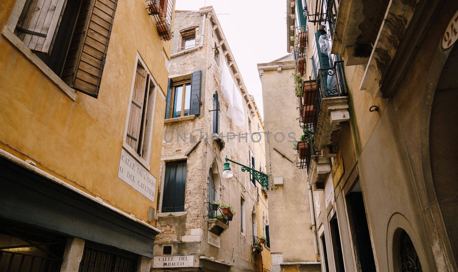 An ancient street lamp, on the corner of the front of the house, on the street in Venice, Italy.
