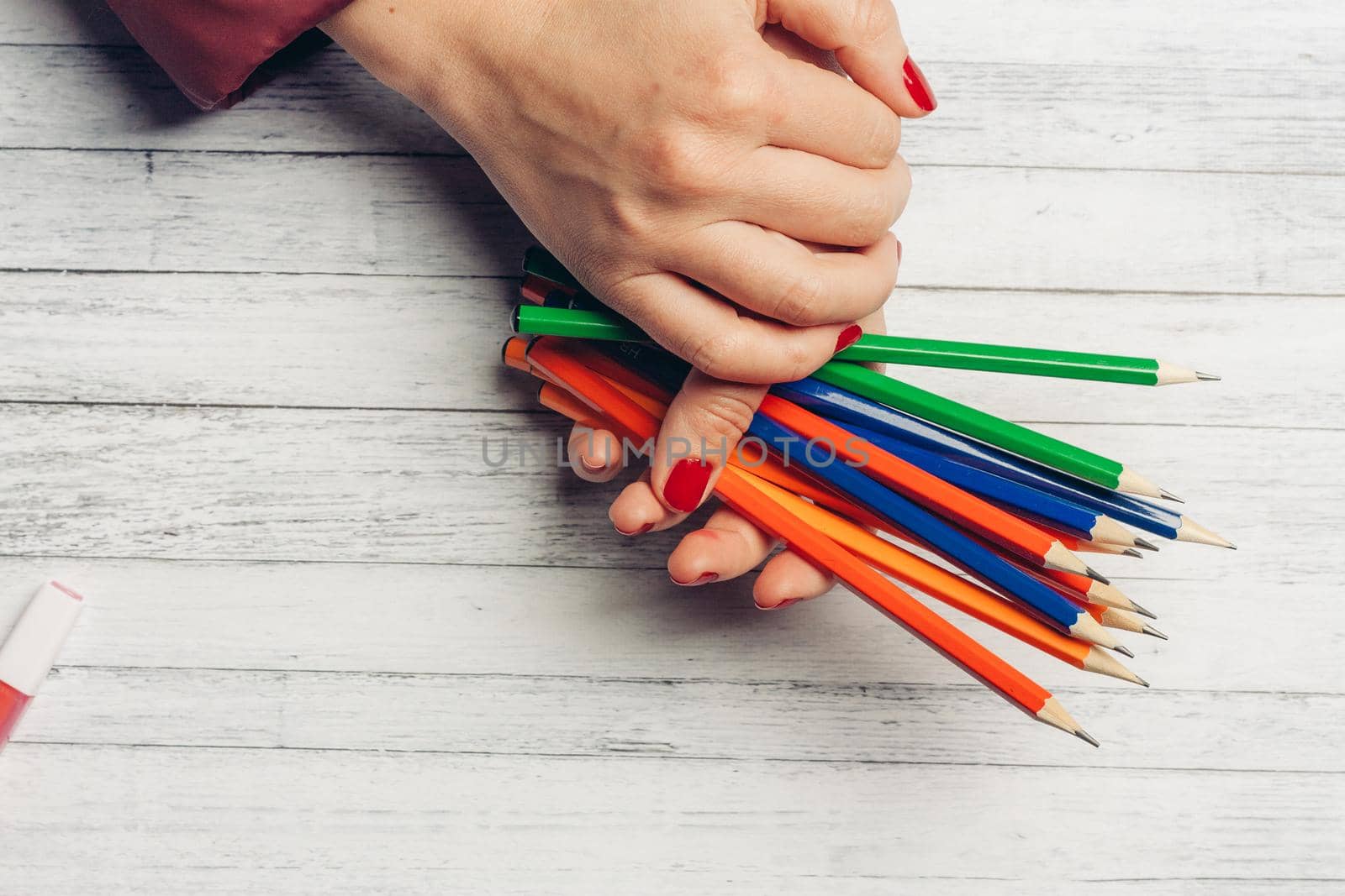 bright colored pencils in woman hands on wooden background cropped view by SHOTPRIME
