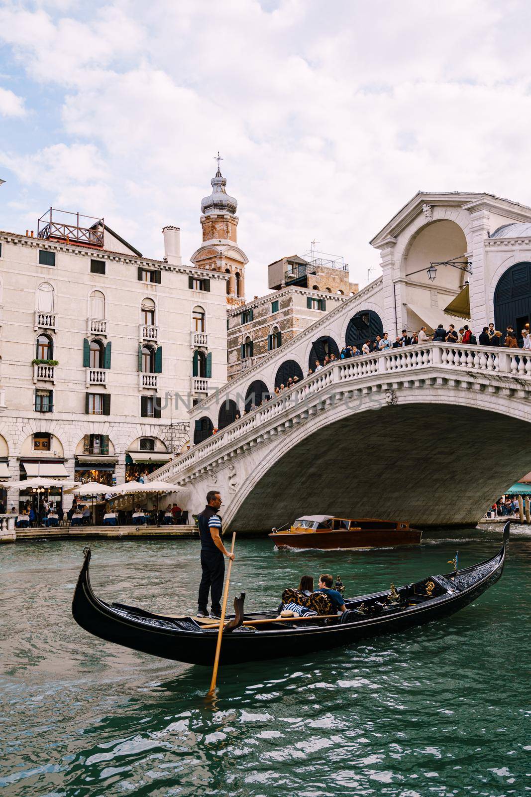 The beautiful Ponte di Rialto Bridge over Central Grand Canal in Venice, Italy, with shops, beautiful views and lots of people. Near boat station of the same name, the street leads to San Marco
