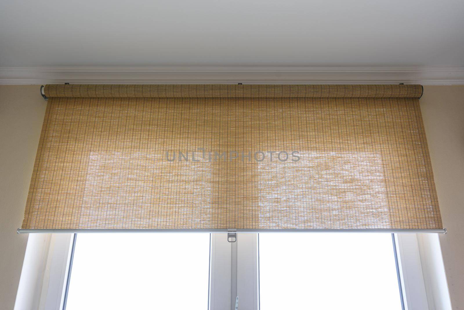 Roller blinds made of thin bamboo on the window by Madhourse