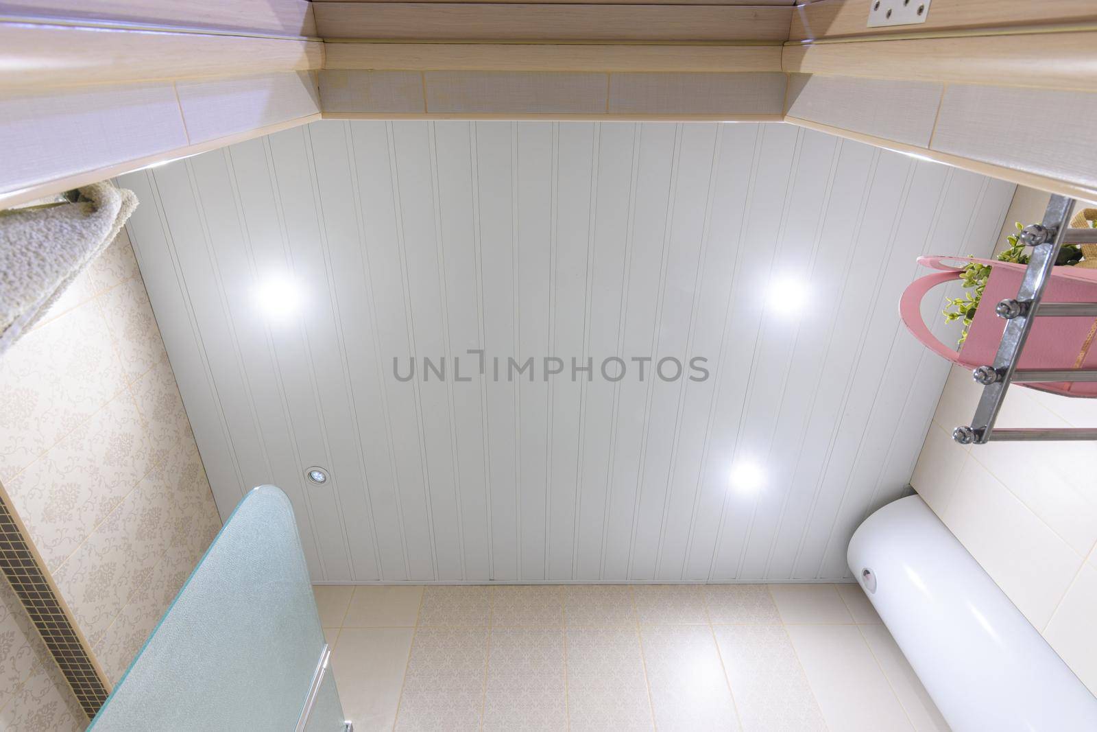 Bathroom ceiling made of white metal panels, with built-in lights, one of which has burned out