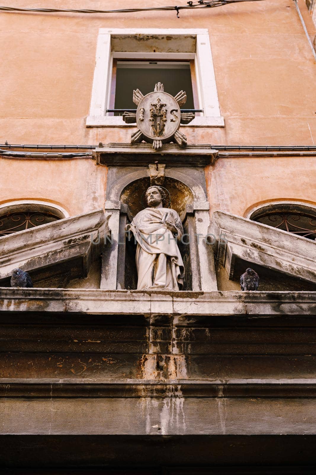 Close-ups of building facades in Venice, Italy. Ancient stone statue above the door.