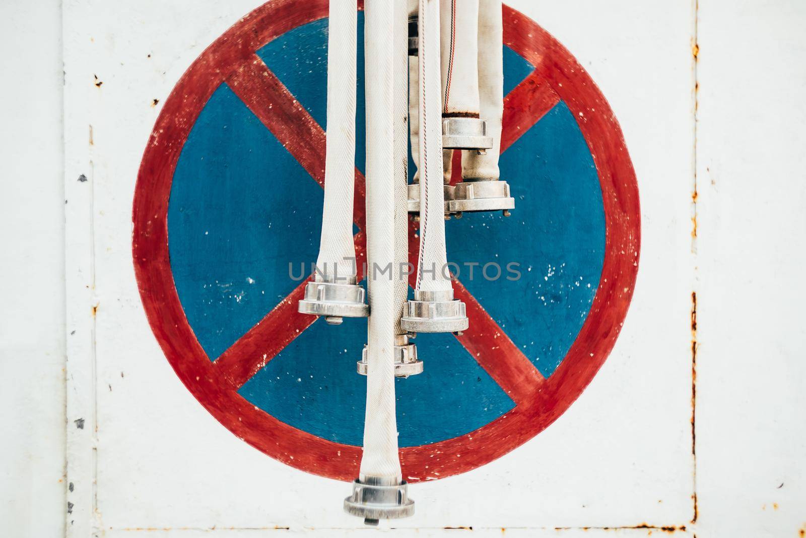 Fire hoses amid metal wall with parking sign banned