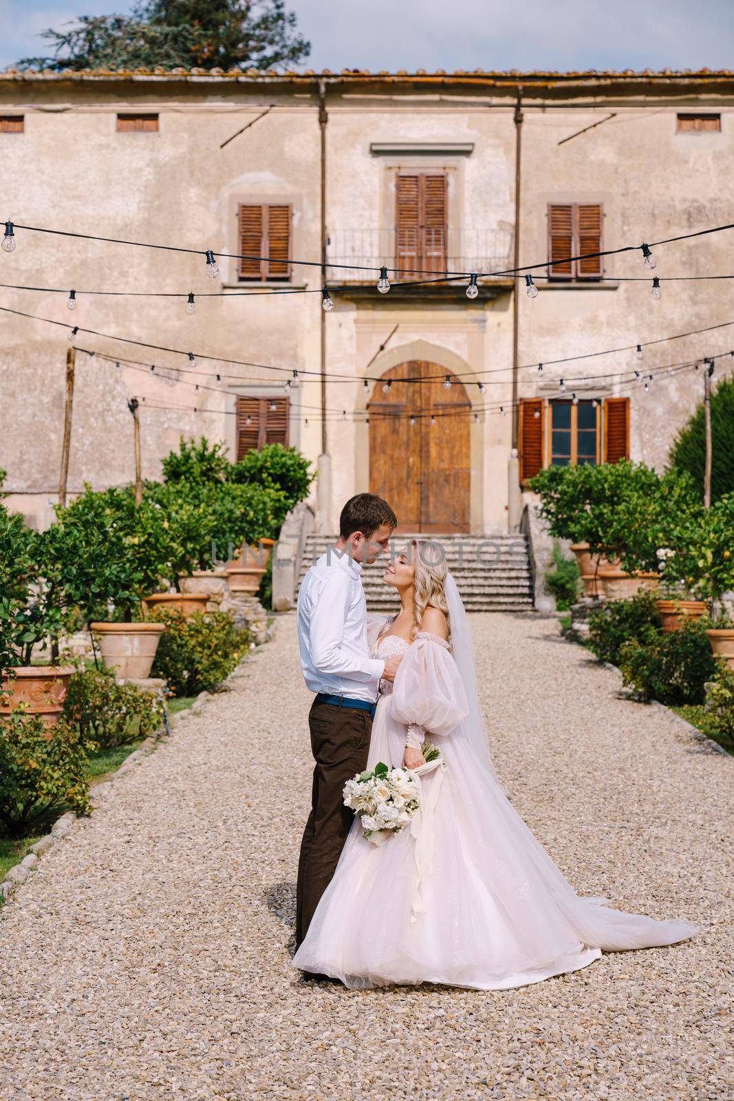 Wedding in Florence, Italy, in an old villa-winery. Wedding couple walks in the garden. Loving bride and groom. by Nadtochiy