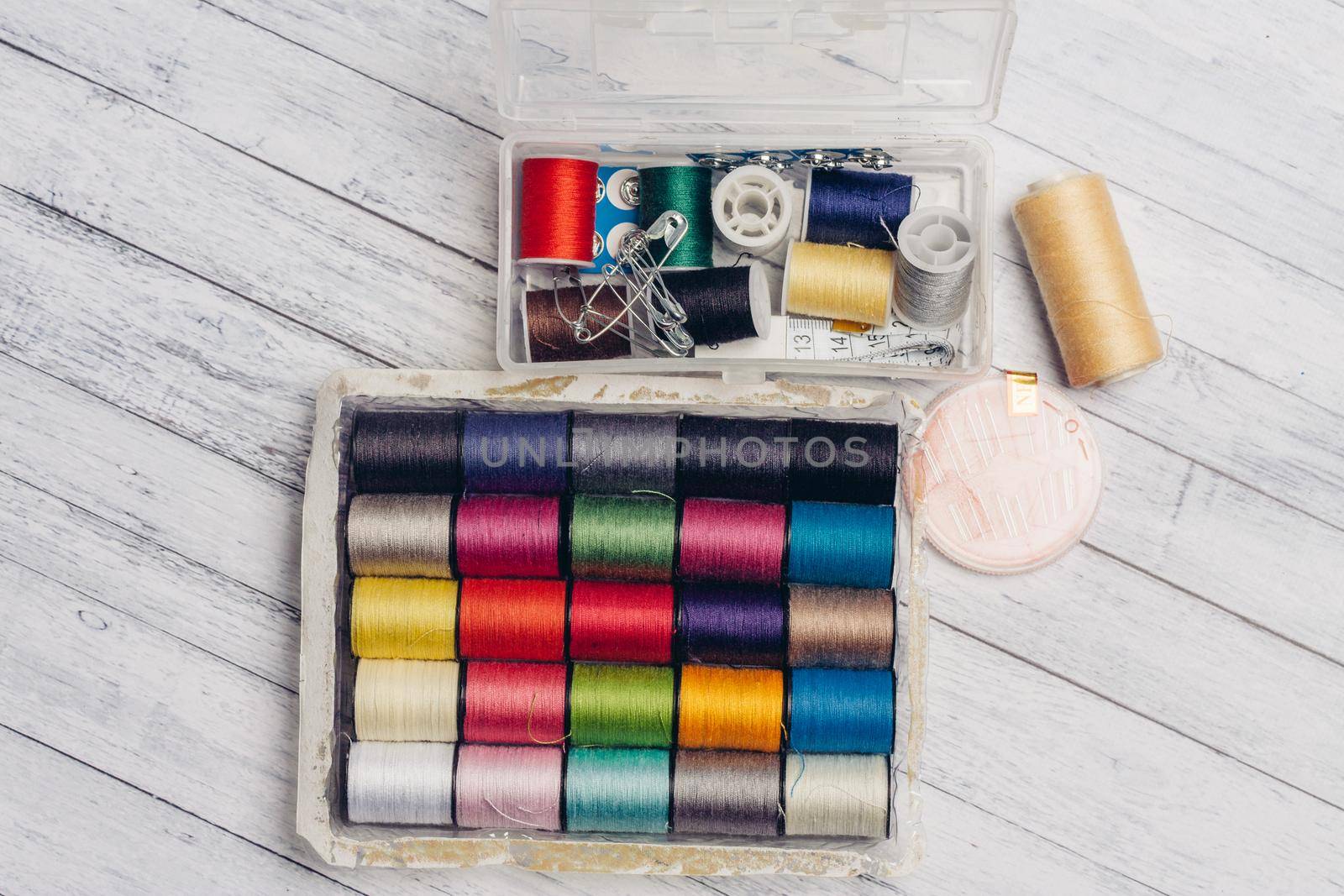 ball of multicolored threads in a box and sewing supplies needles and pins on a wooden table by SHOTPRIME
