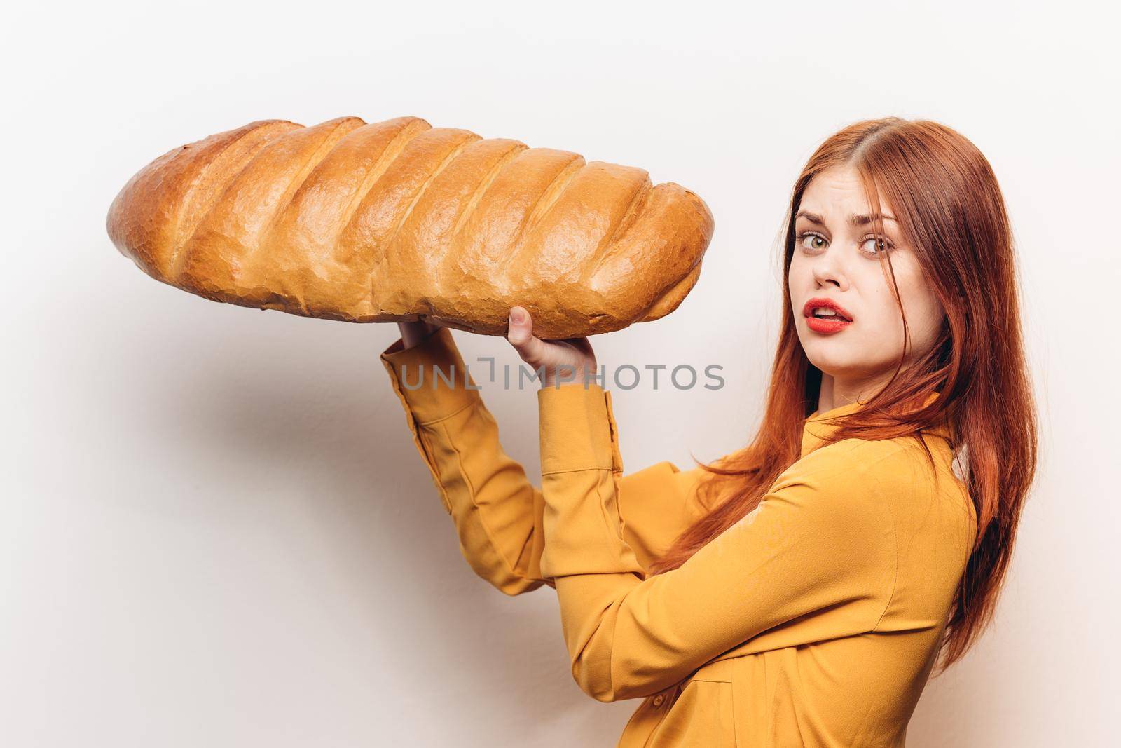 woman in a yellow shirt with a huge loaf in her hands a flour product light background. High quality photo